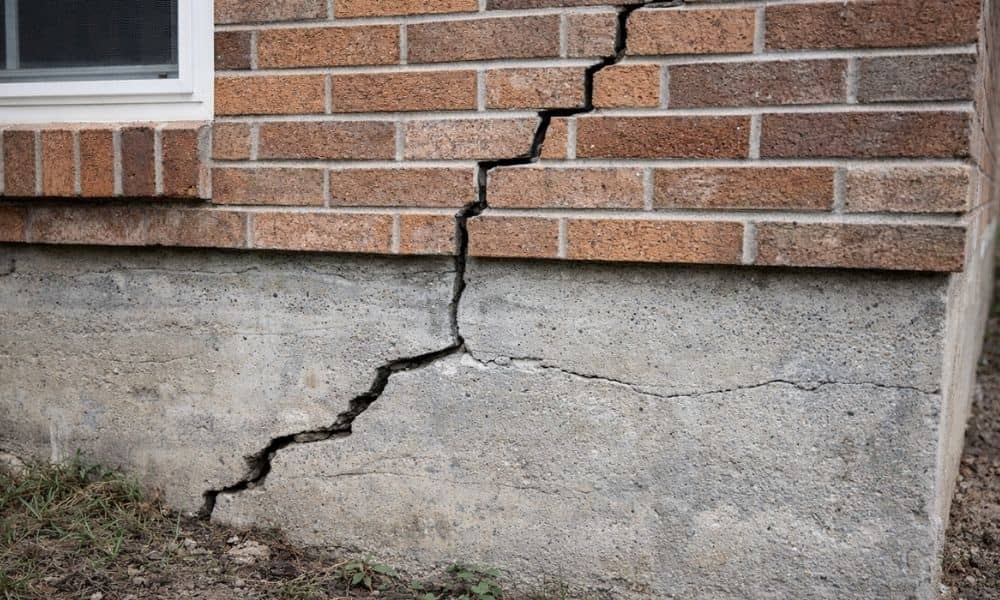 Differential settlement causing diagonal cracking in a building foundation due to uneven soil conditions