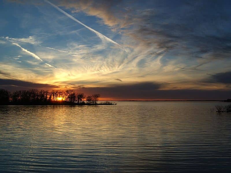 Sunset over Ray Roberts Lake with calm water and tree-lined shoreline near Denton, Texas